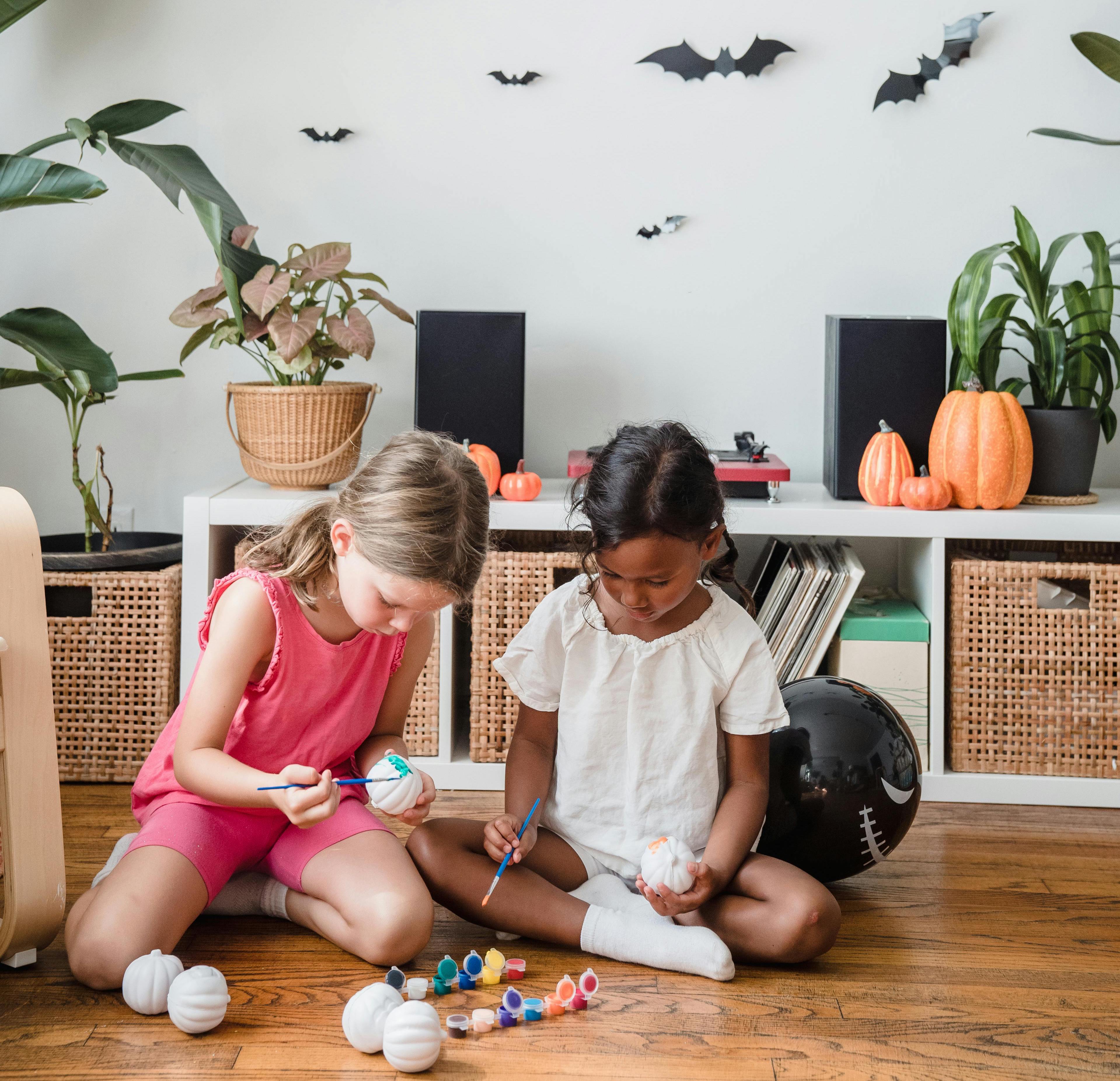 Children sitting on floor, playing with paint. 