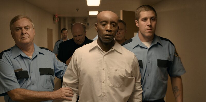 Rob Morgan is walked down an ominous hallway