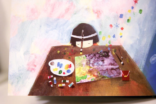 Young girl with a paintbrush attached to her head painting