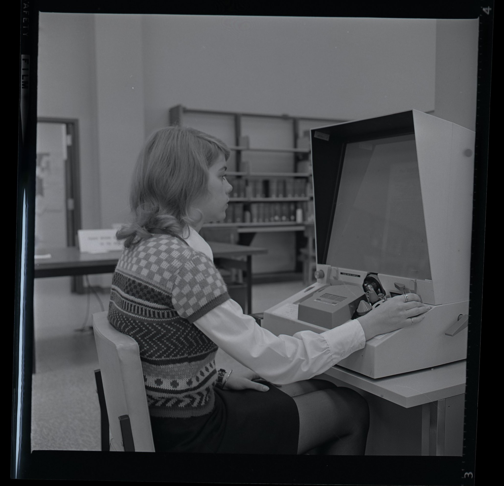 a young woman using a microfilm machine in the Ben West Library