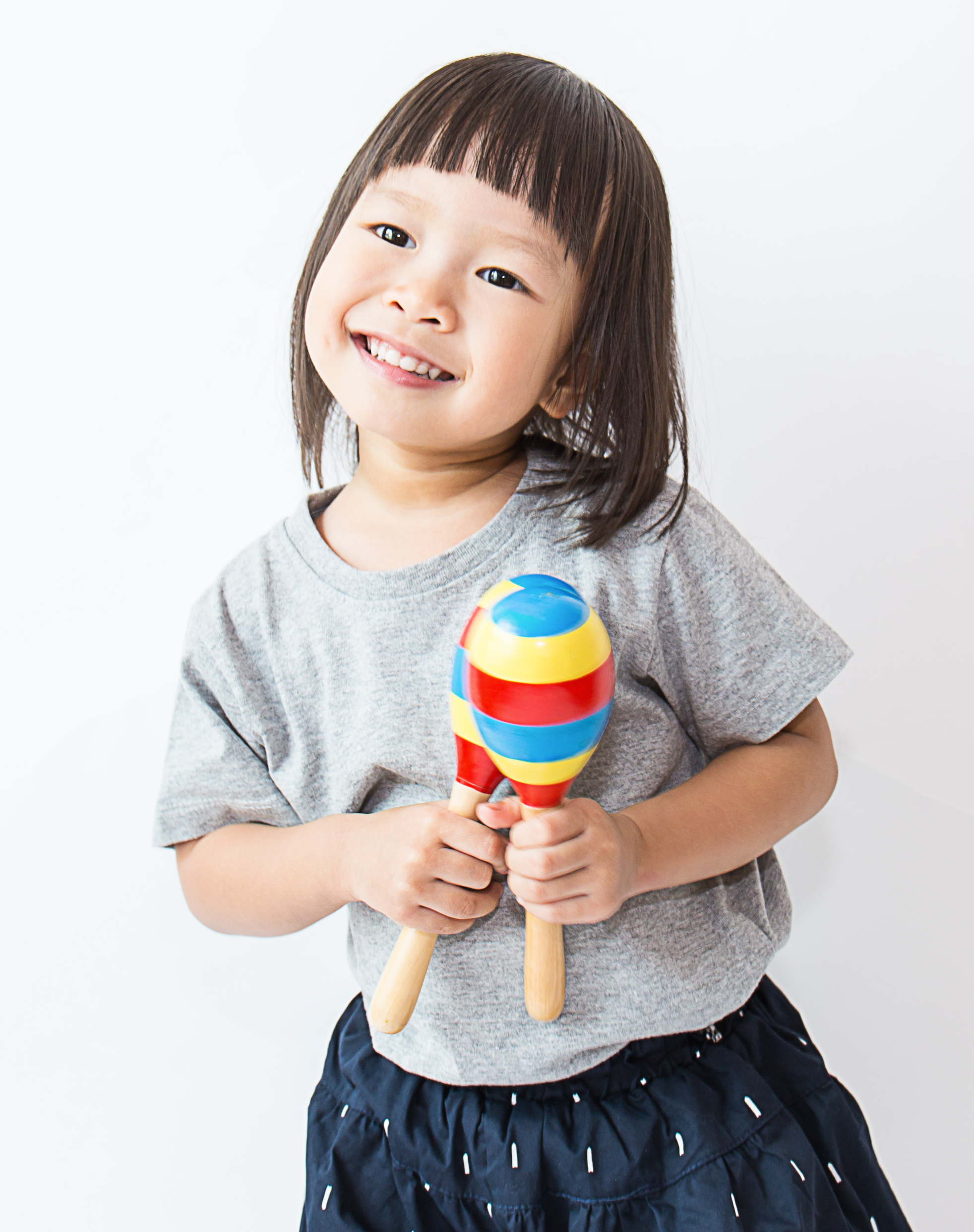 Little girl holding striped maracas.