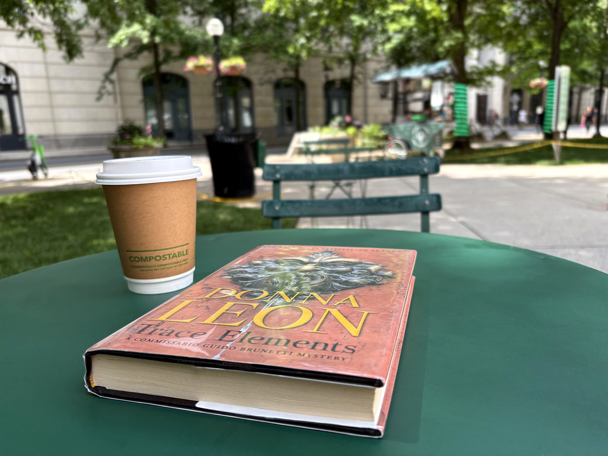 A cup of to-go coffee and a library book on a cafe table outside Nashville's Main Library downtown.