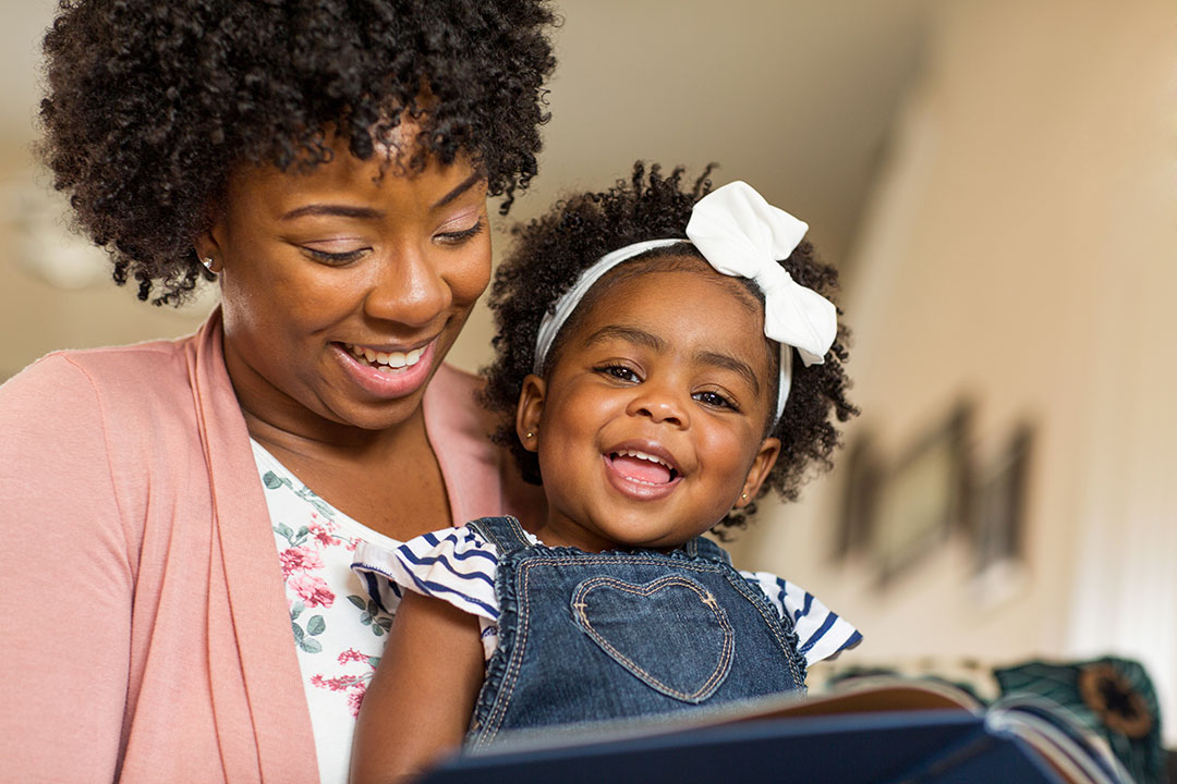 Woman with a baby on her lap looking at a book together.