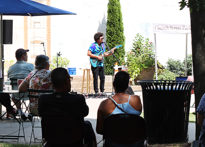 Group of people in the library courtyard sitting at bistro tables.