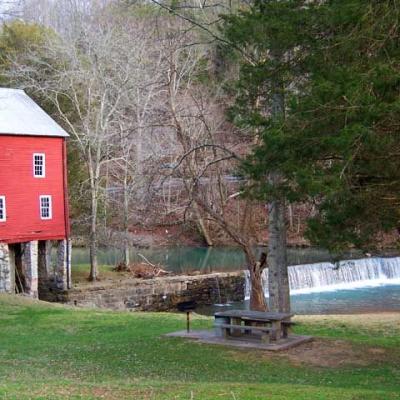 Green lawn with red barn and forest in the background