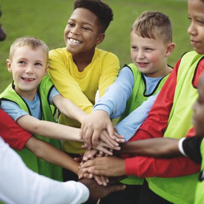 Group of kids with their hands layered before doing a cheer.