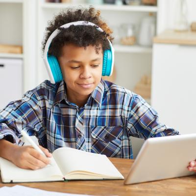 Boy reading with headphones and a tablet.