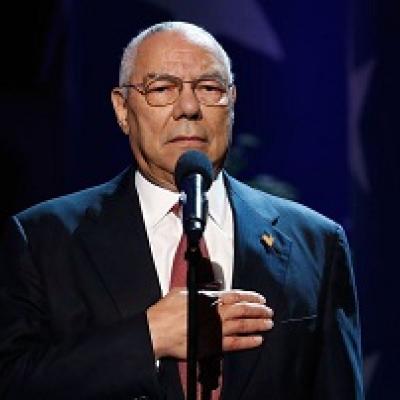 Headshot of a man in a suit against a black background.