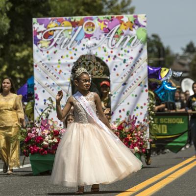 Girl standing in front of a parade float that reads "Fil Am" for Filipino American History Month