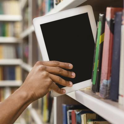 Hand placing a tablet computer on a bookshelf.