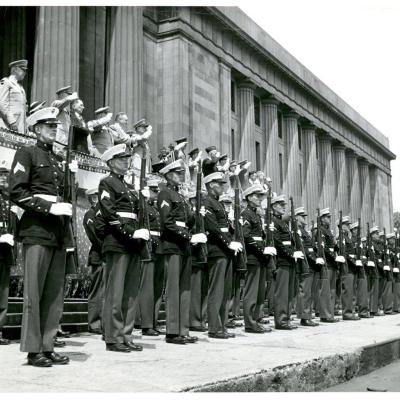 Black and white photo of marines in dress blues in front of the War Memorial building.