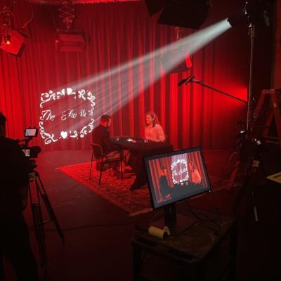 TV studio with red curtains and soft lighting.