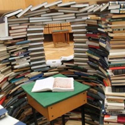 Stacks of books in a semi-circle surrounding a desk.