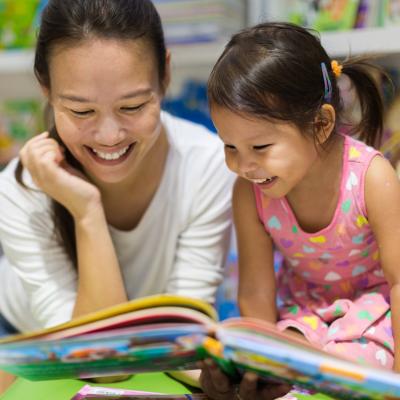 Mother and toddler reading together at a table.