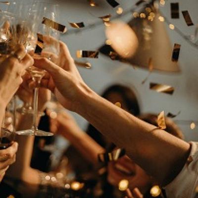 Close up of raised hands holding champagne glasses.