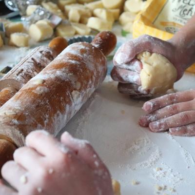 Hands rolling dough with a rolling pin.