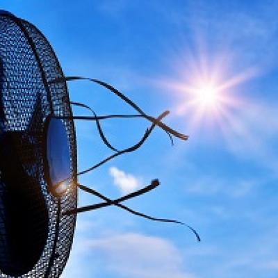 Desktop fan blowing air with the sun in a clear sky.