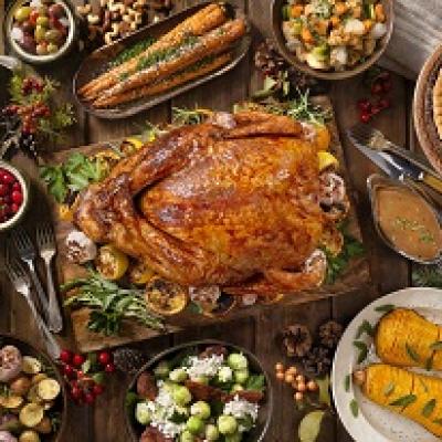 Thanksgiving table with turkey, potatoes, pie, and other dishes.