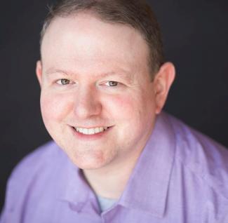 Smiling white man in lavender collared shirt on black background