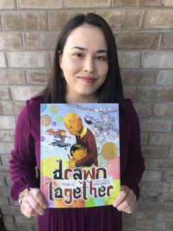 Smiling woman holding picture book titled Drawn Together. 