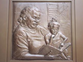 Mother holding child from part of the large bronze doors at Main Library.
