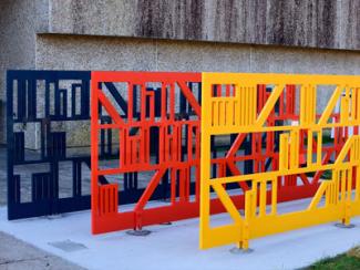 Shelves is a steel bike rack that depicts red, yellow, and blue books on shelves.